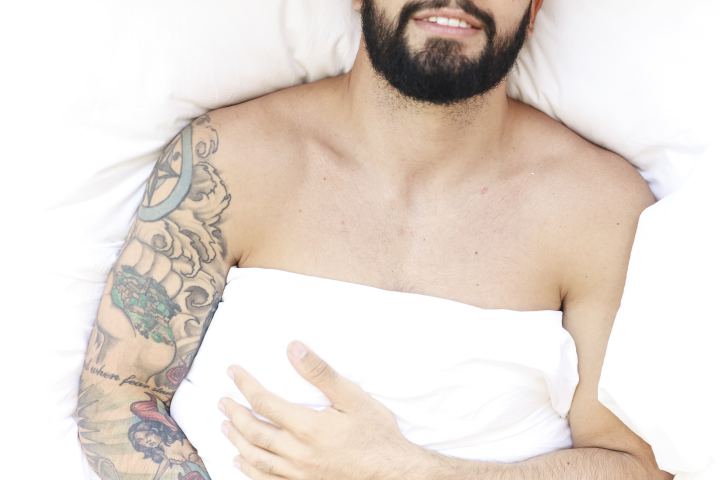 Man in bed met dekbed over hem