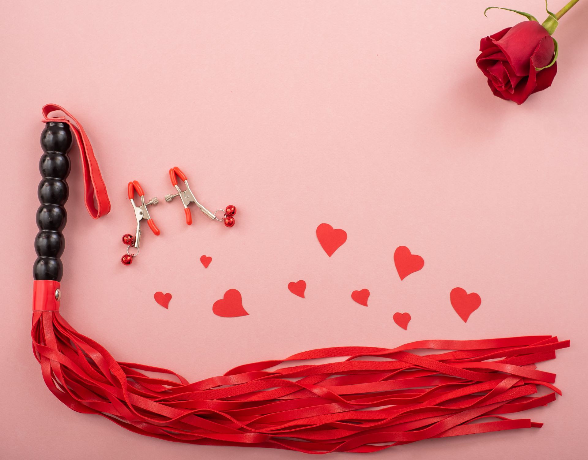 Rode zweep en tepelklemmen met roze achtergrond